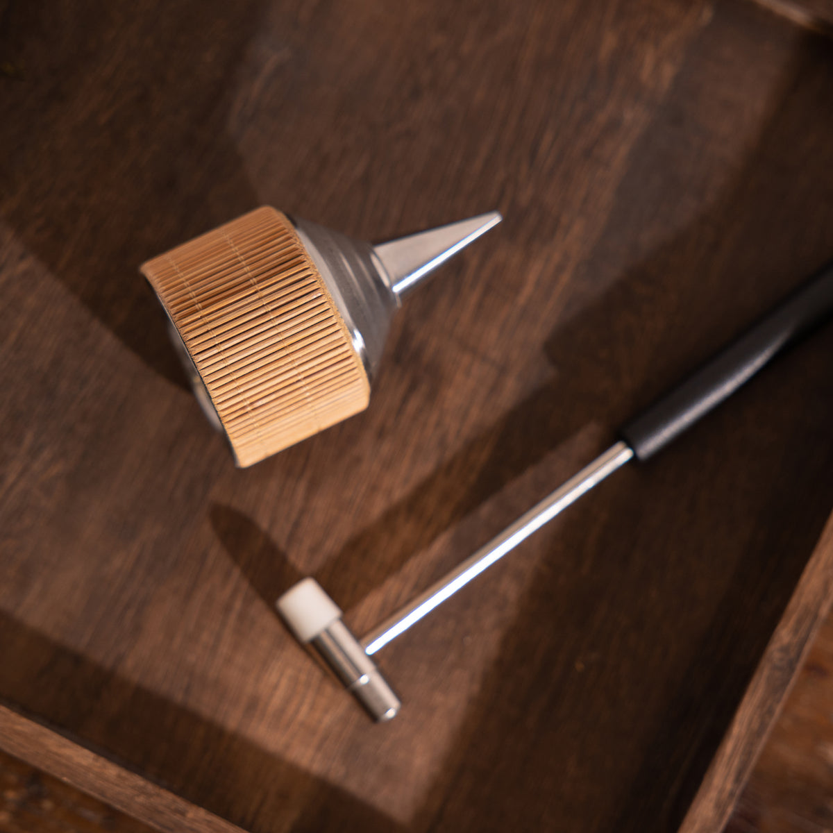 A powder incense set consisting of a metal dropper and small mallet, on a wooden tray