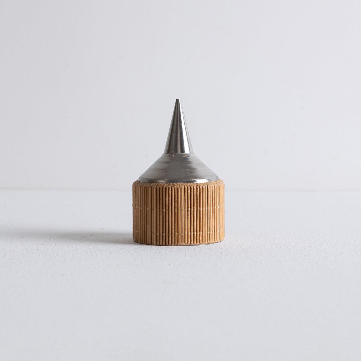 Side view of Kin Object's metal incense powder dropper with bamboo details