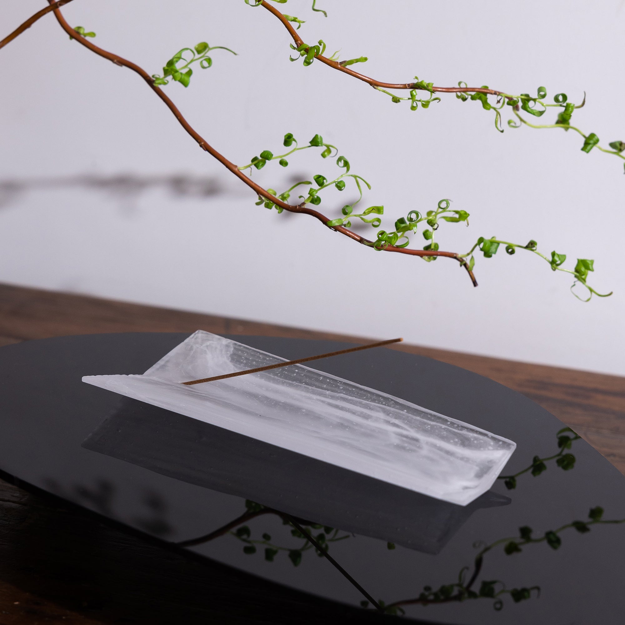 Kin Object's liuli glass incense holder with wood grain patterns on a black table