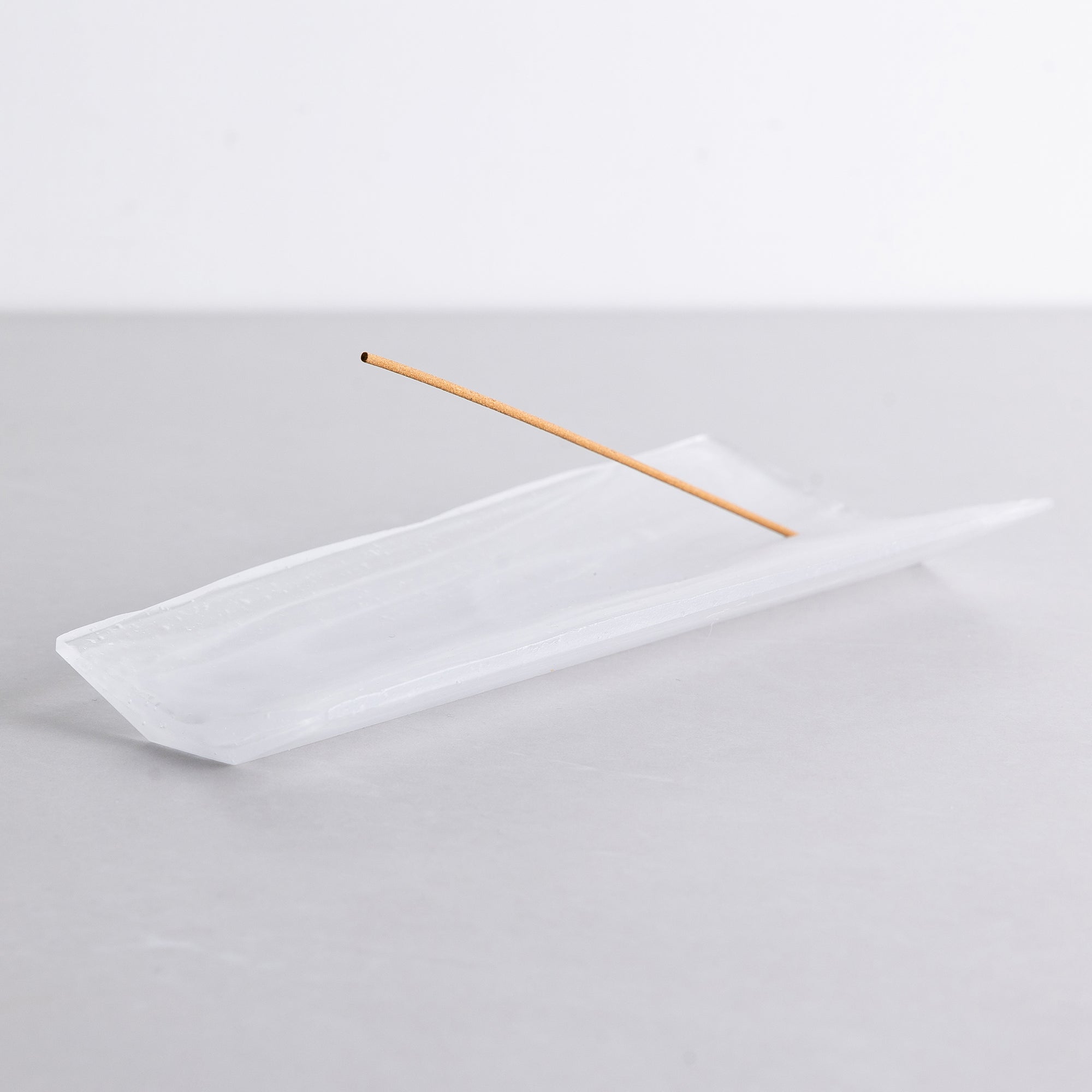Kin Object's liuli glass incense holder with wood grain patterns on a black table