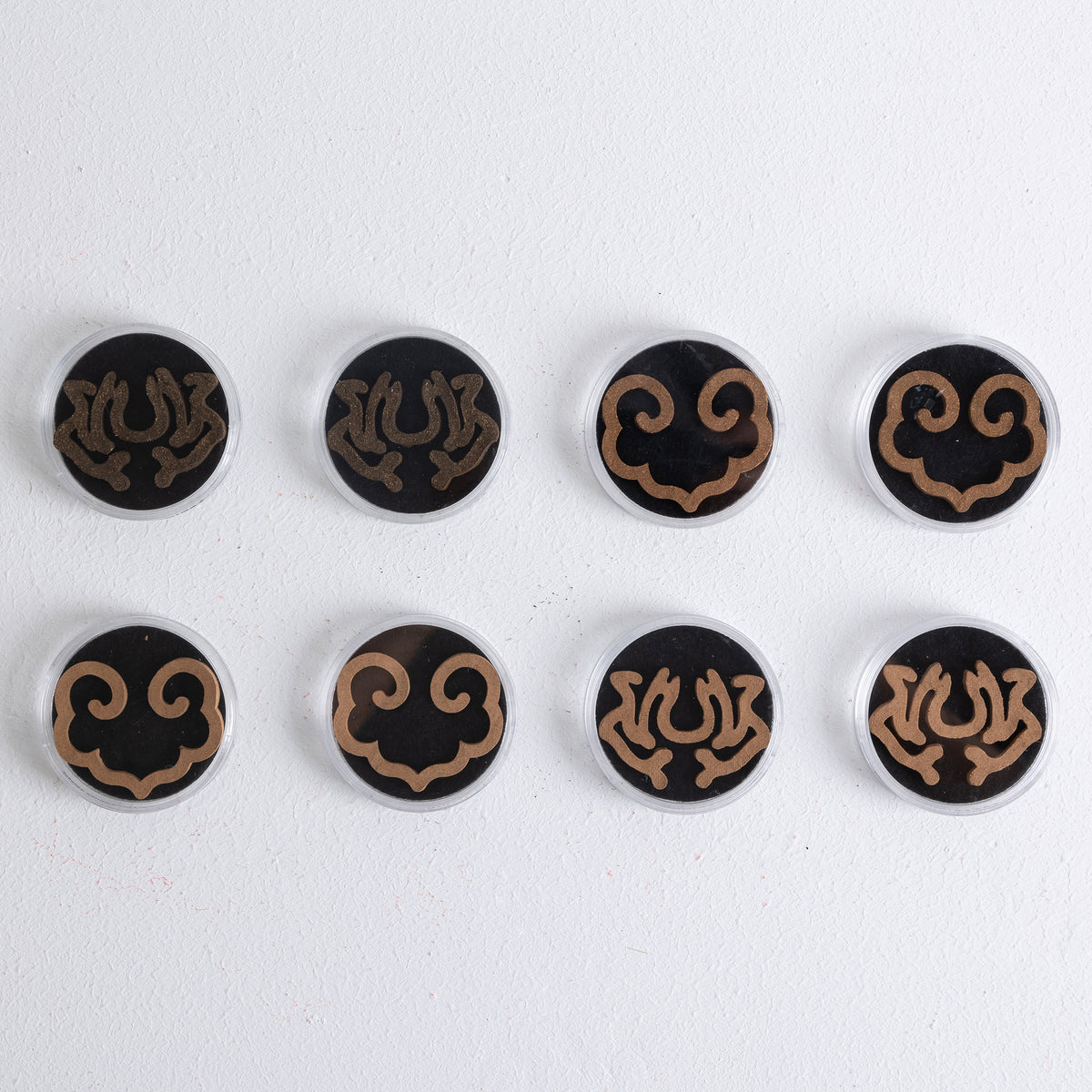 Brown lotus and ruyi-shaped incense seals in clear plastic containers, part of 8-piece set by Kin Objects