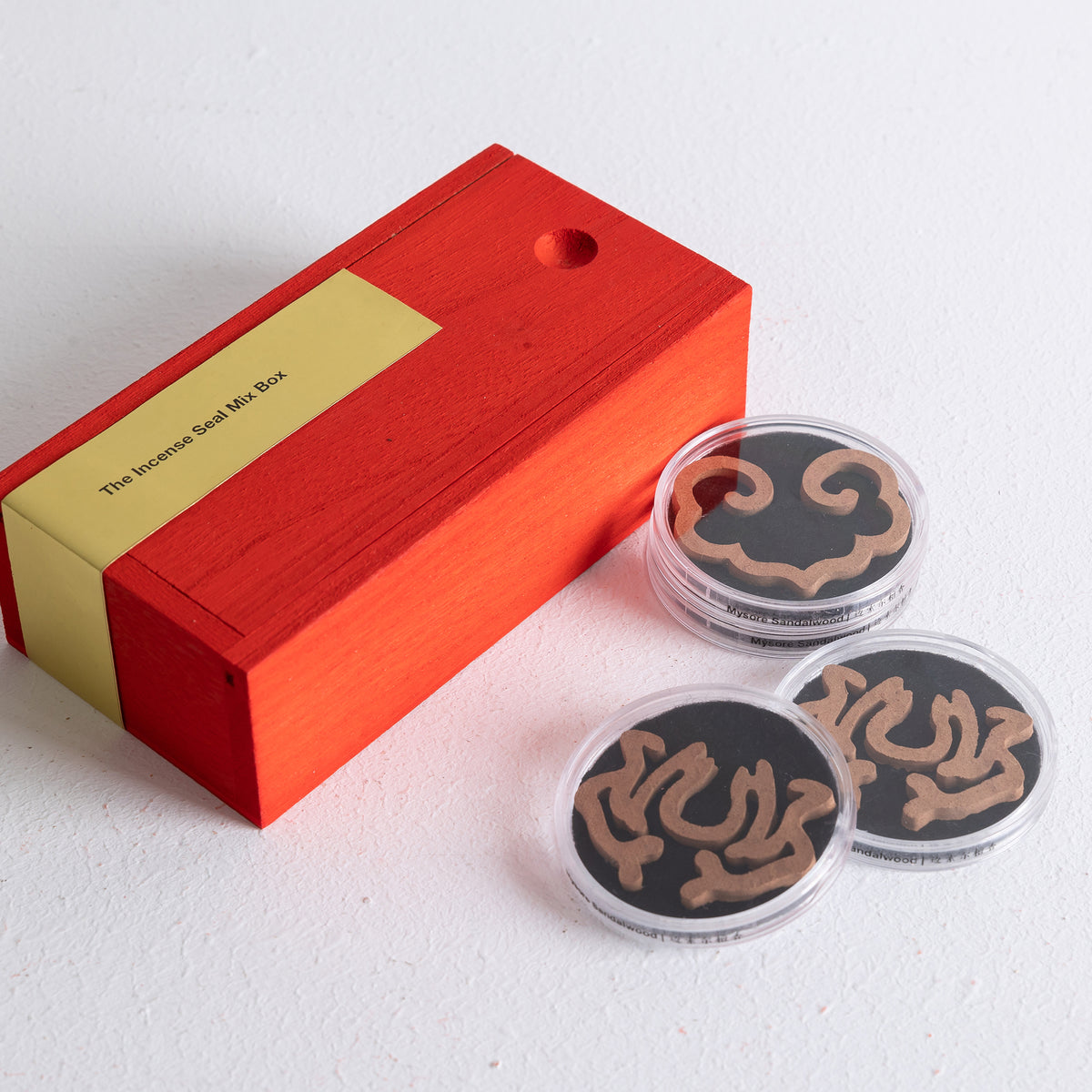 Red wooden box containing 8 incense seals in lotus and ruyi designs, brown and dark brown colors