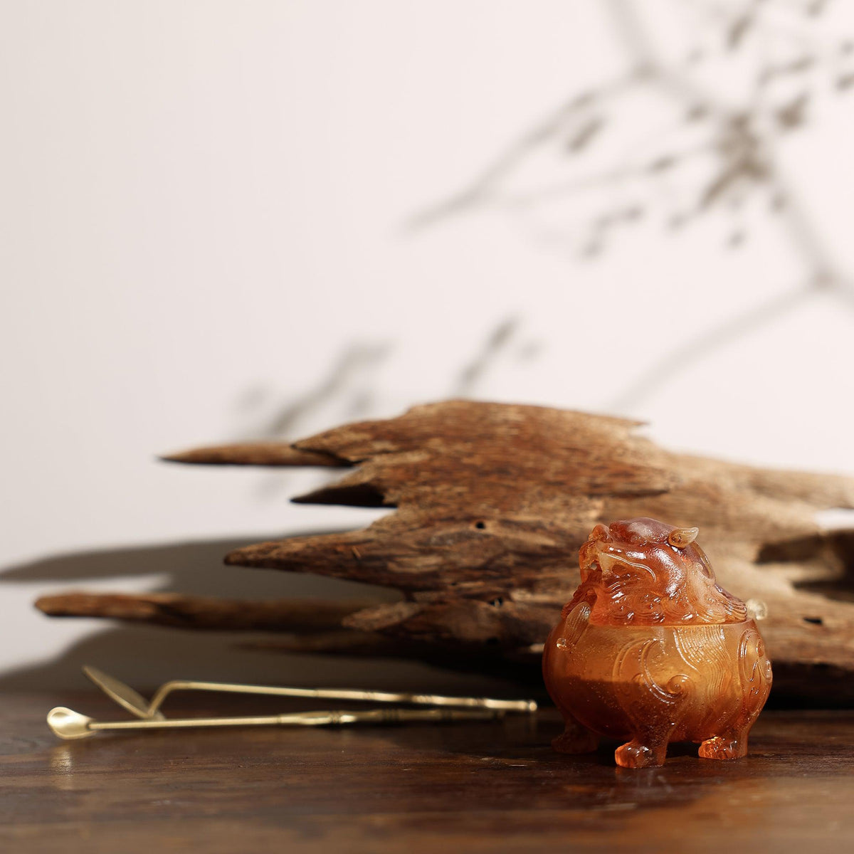 Side view of a glass lion incense burner with incense powder tools