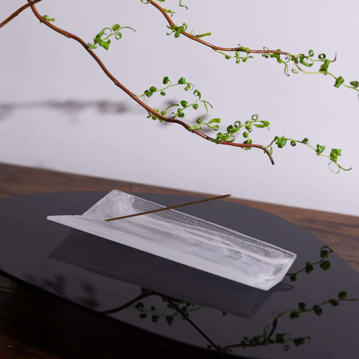 Kin Object&#39;s liuli glass incense holder with wood grain patterns on a black table