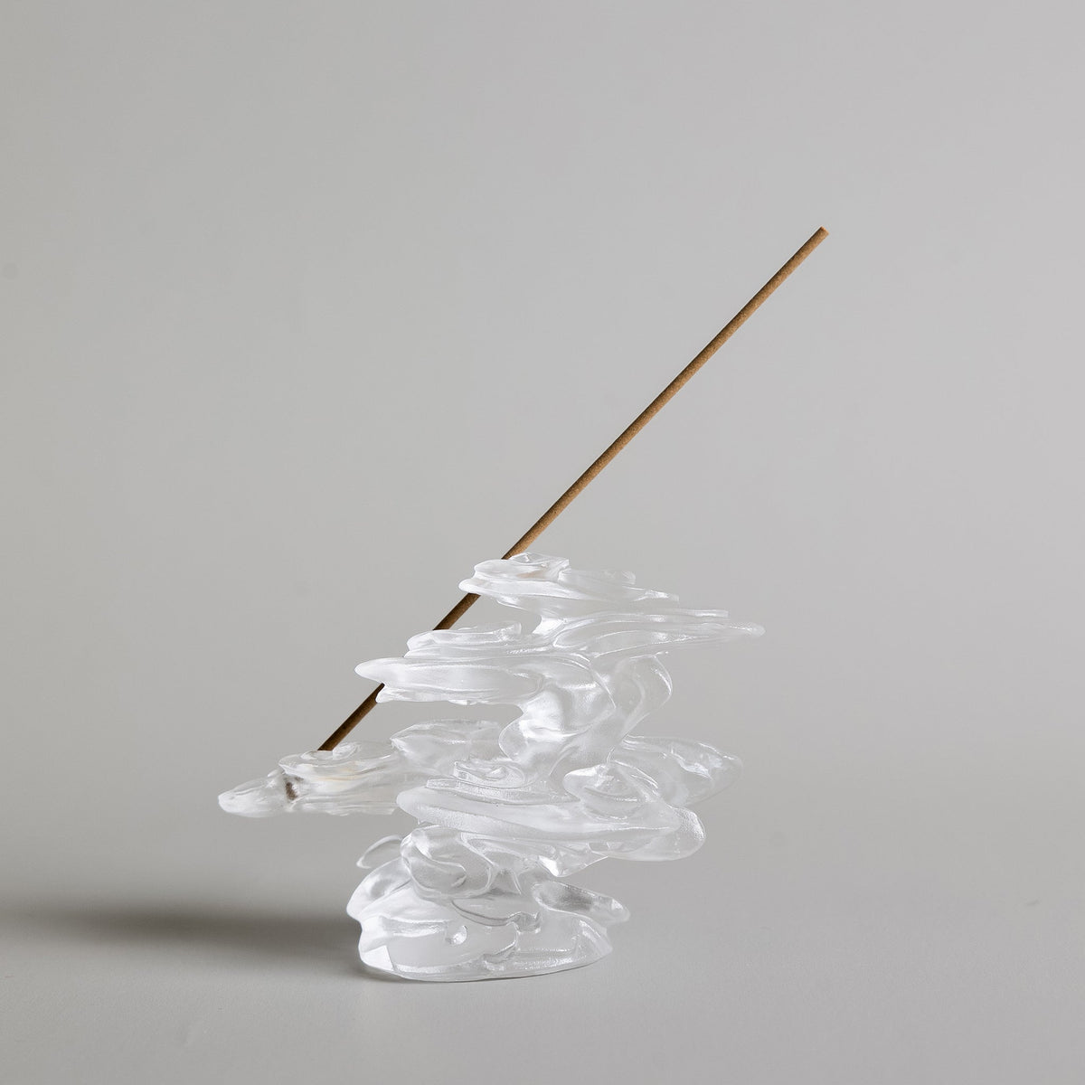 A cloud-shaped glass incense burner with an incense stick