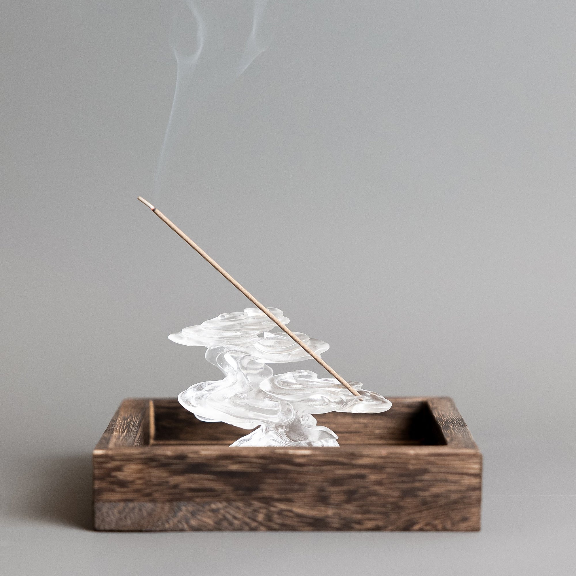 A burning incense stick in a cloud-inspired liuli crystal incense holder