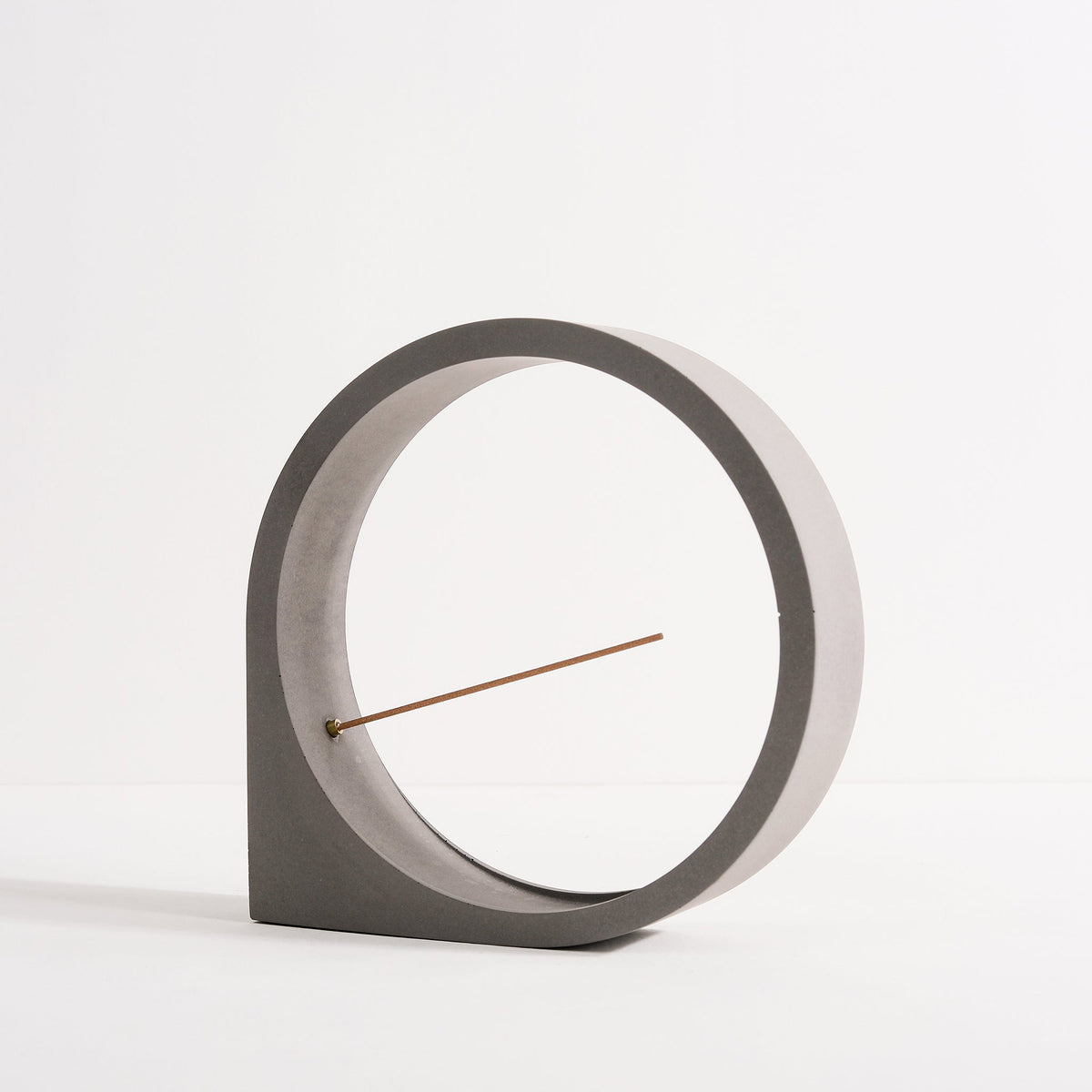 Front angled view of a concrete round incense holder by Kin Objects
