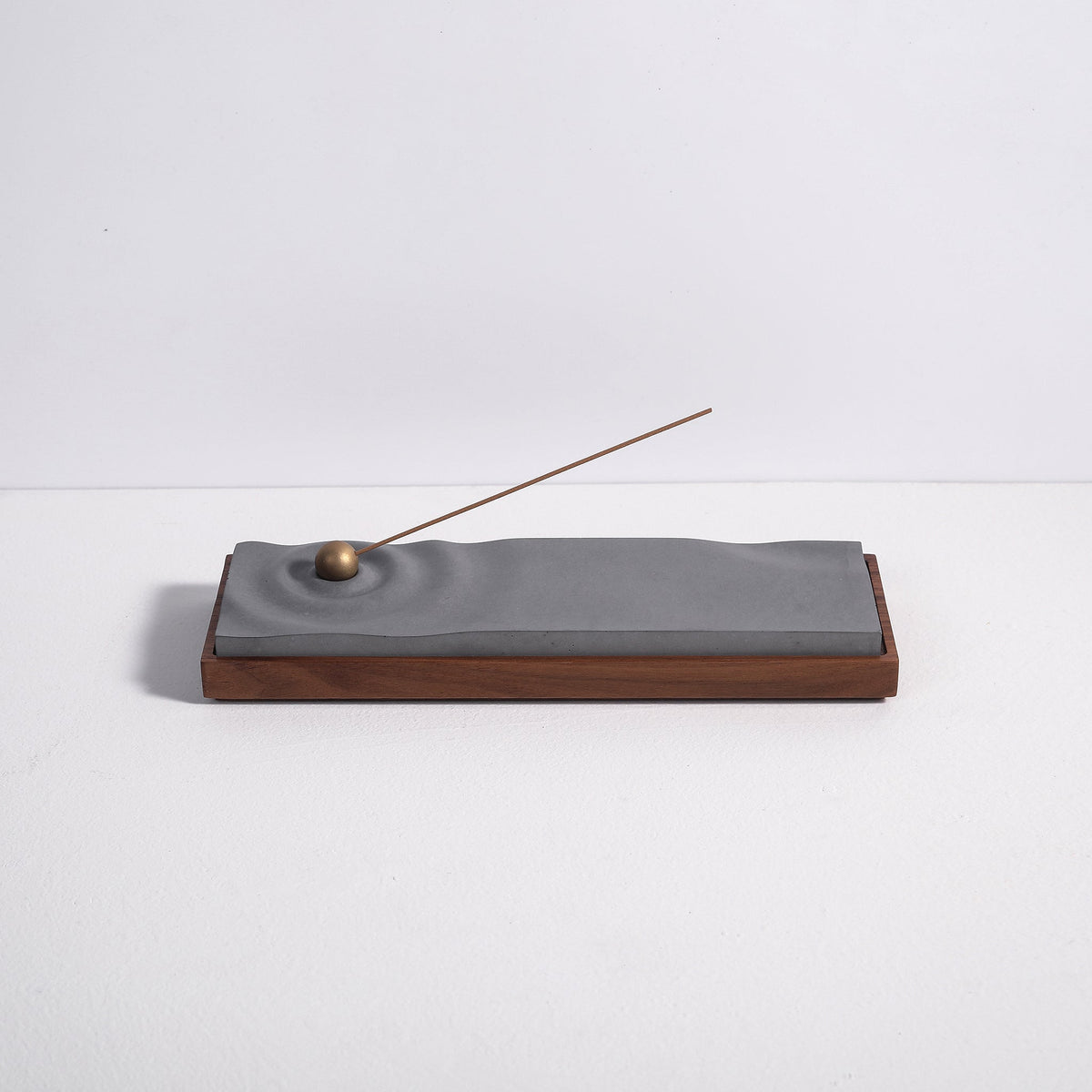 Concrete ripple incense burner with walnut base by Kin Objects